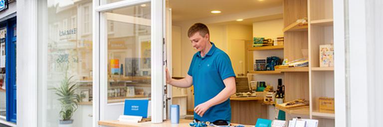 Independent shop owner opening a bright Limavady storefront and preparing the counter for the trading day